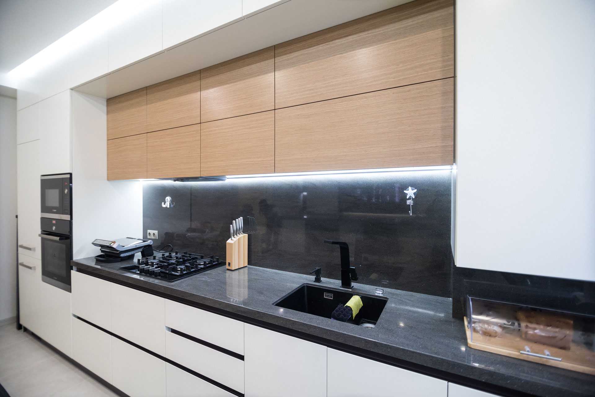 Cuisine moderne rénovée avec meubles en bois et plan de travail noir – AJLP RENOV', expert en rénovation intérieure et aménagement sur-mesure.